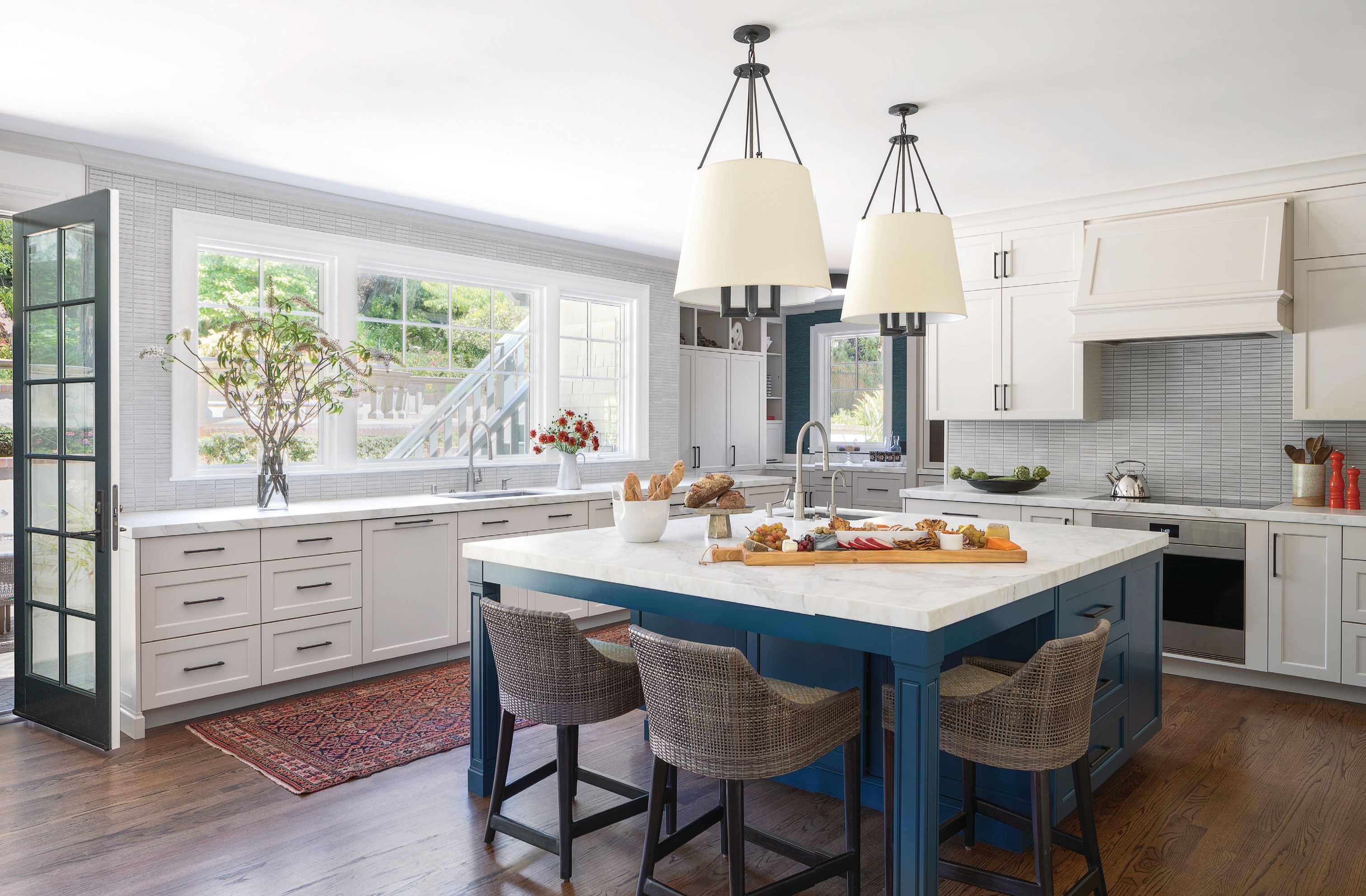 A mosaic backsplash from Ann Sacks, pendants from Visual Comfort and chairs from Palecek grace the bright and functional kitchen. PHOTOGRAPHED BY PAUL DYER AND TIM COY