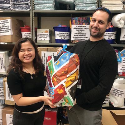 The Welcome Home Project’s Sam Soy (left) presents a package of cleaning and hygiene items to a caseworker for a formerly homeless client PHOTO COURTESY OF ORGANIZATIONS