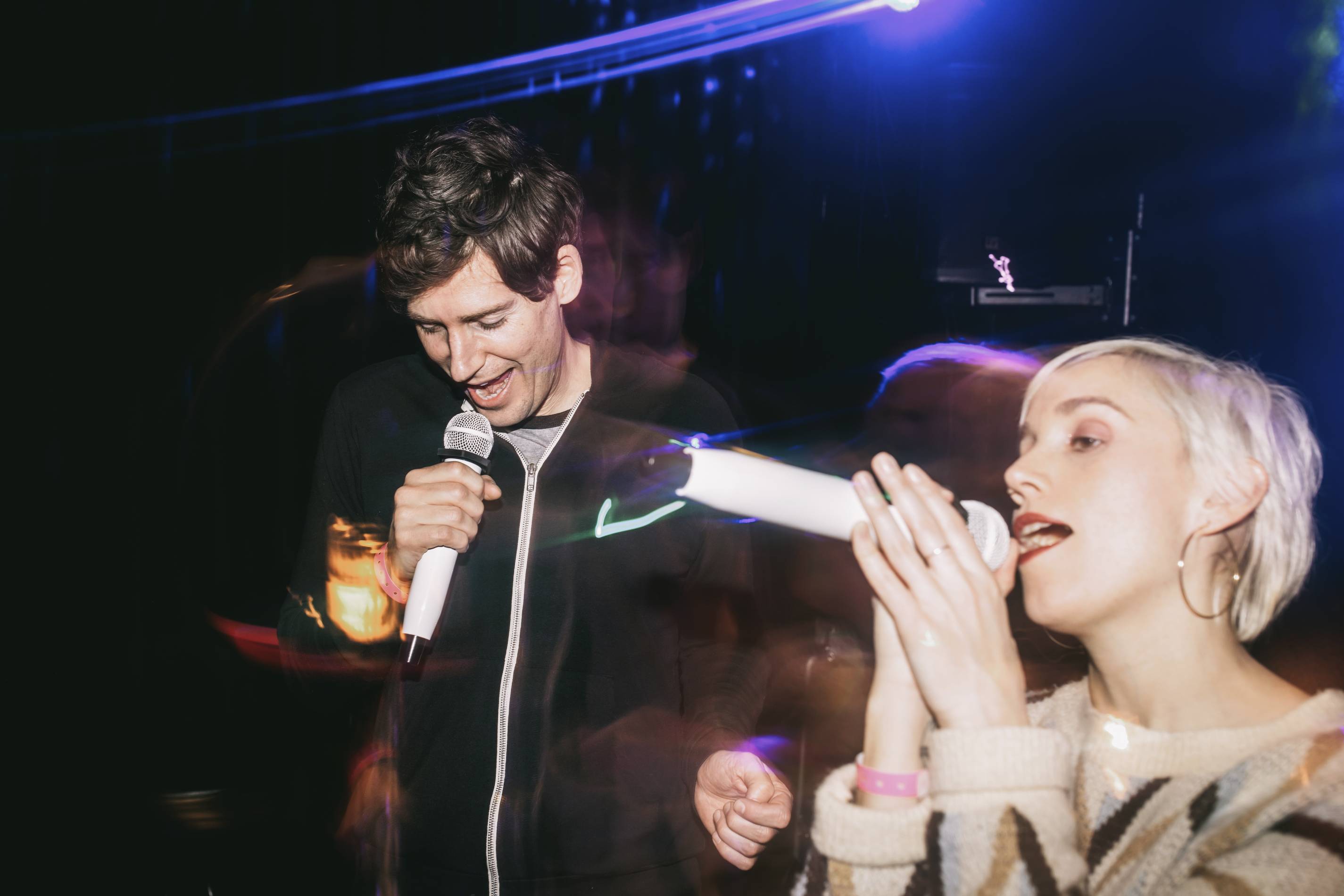 a man and a woman sing karaoke at a bar